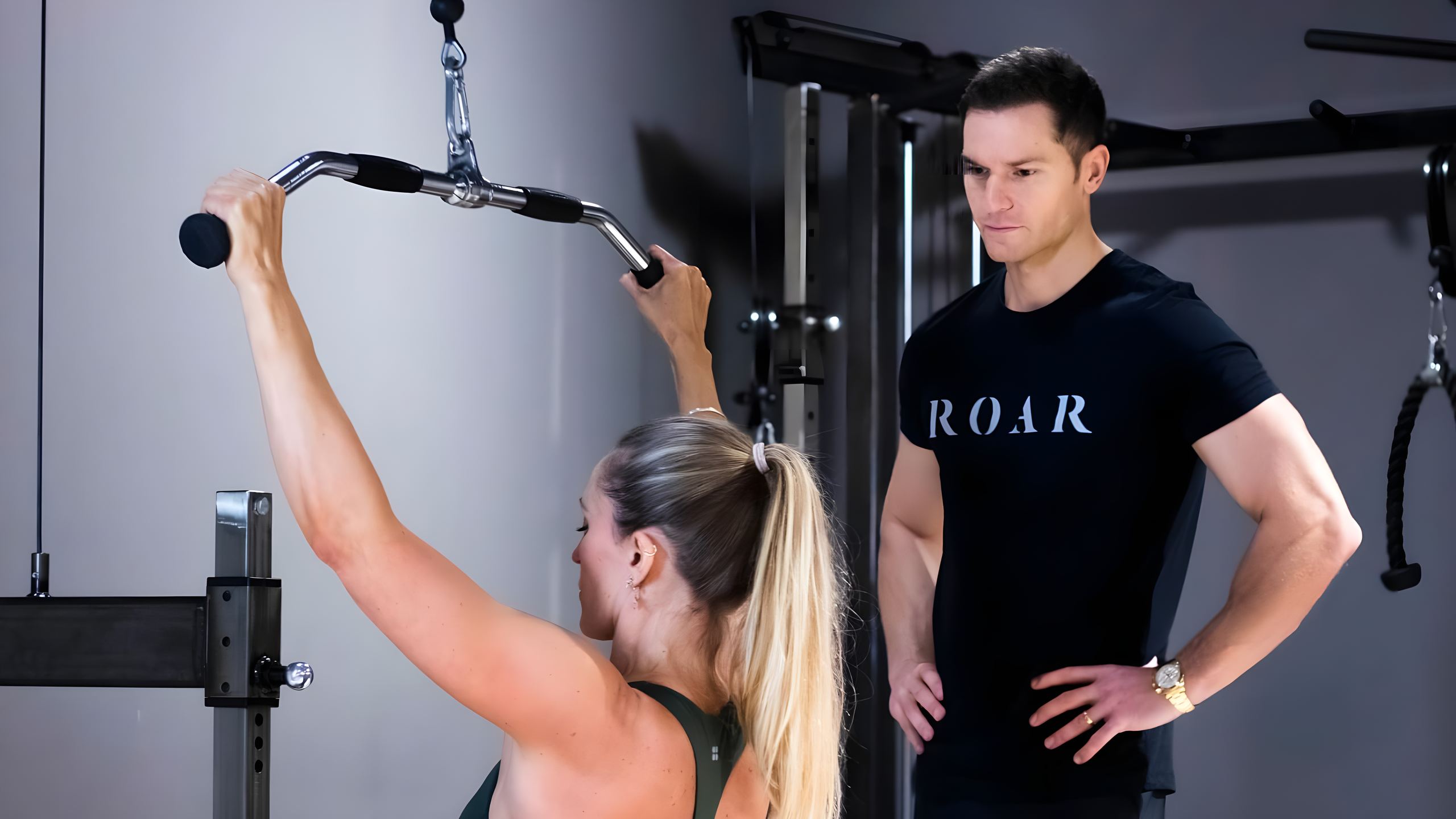 Rich Phillipps coaching a client through a cable lat pulldown at Roar Fitness