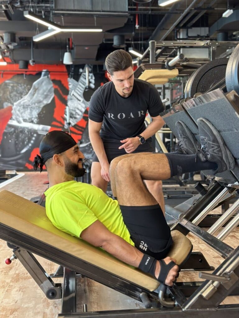DJ Bliss on the leg press with a ROAR personal trainer watching at ROAR Fitness Dubai
