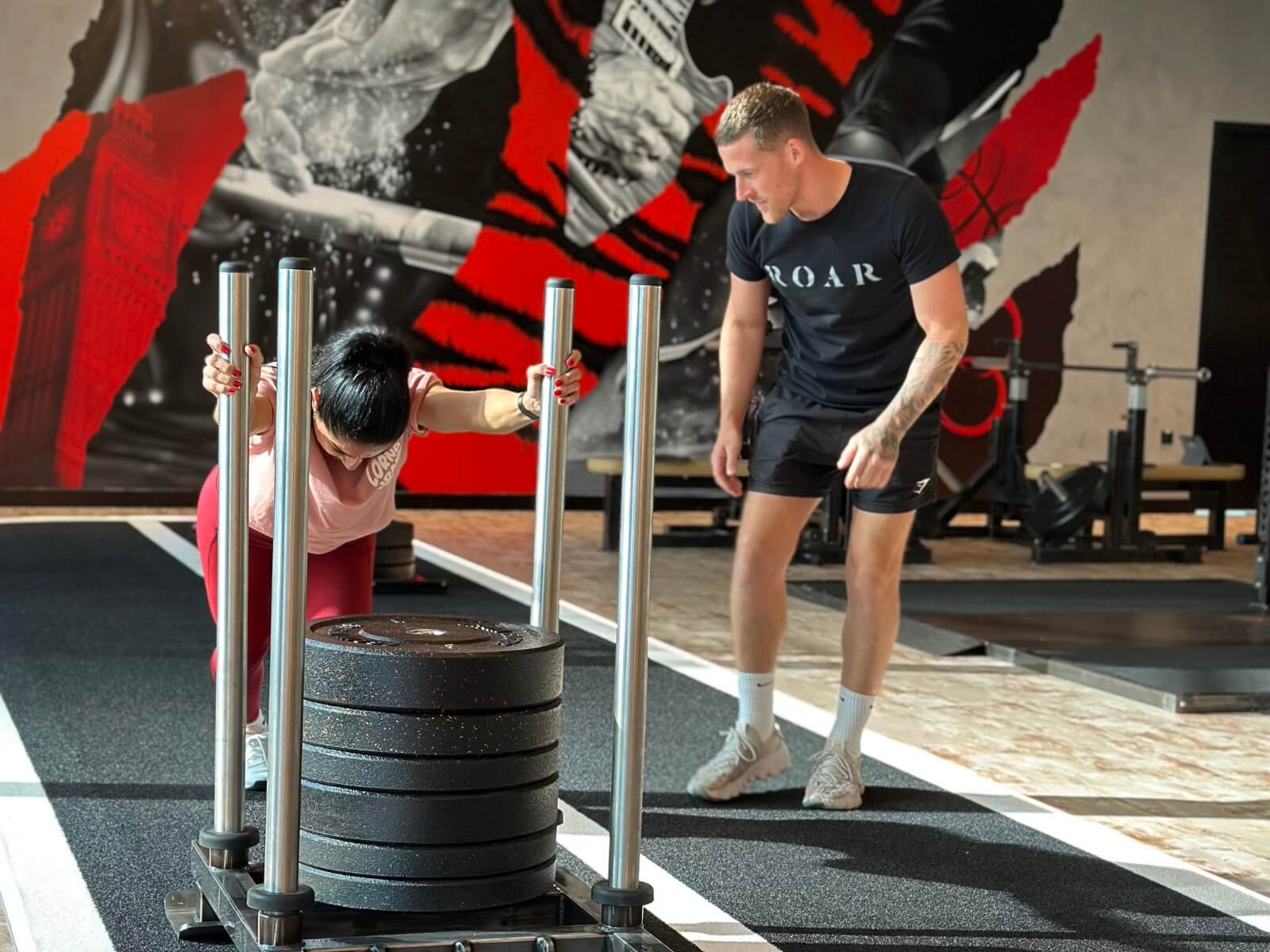 Personal trainer coaching a client through a sled push at Roar Fitness Dubai