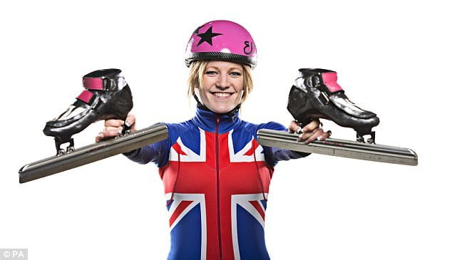 Short track speed skater Elise Christie holding up her skates in a Great Britain race suit
