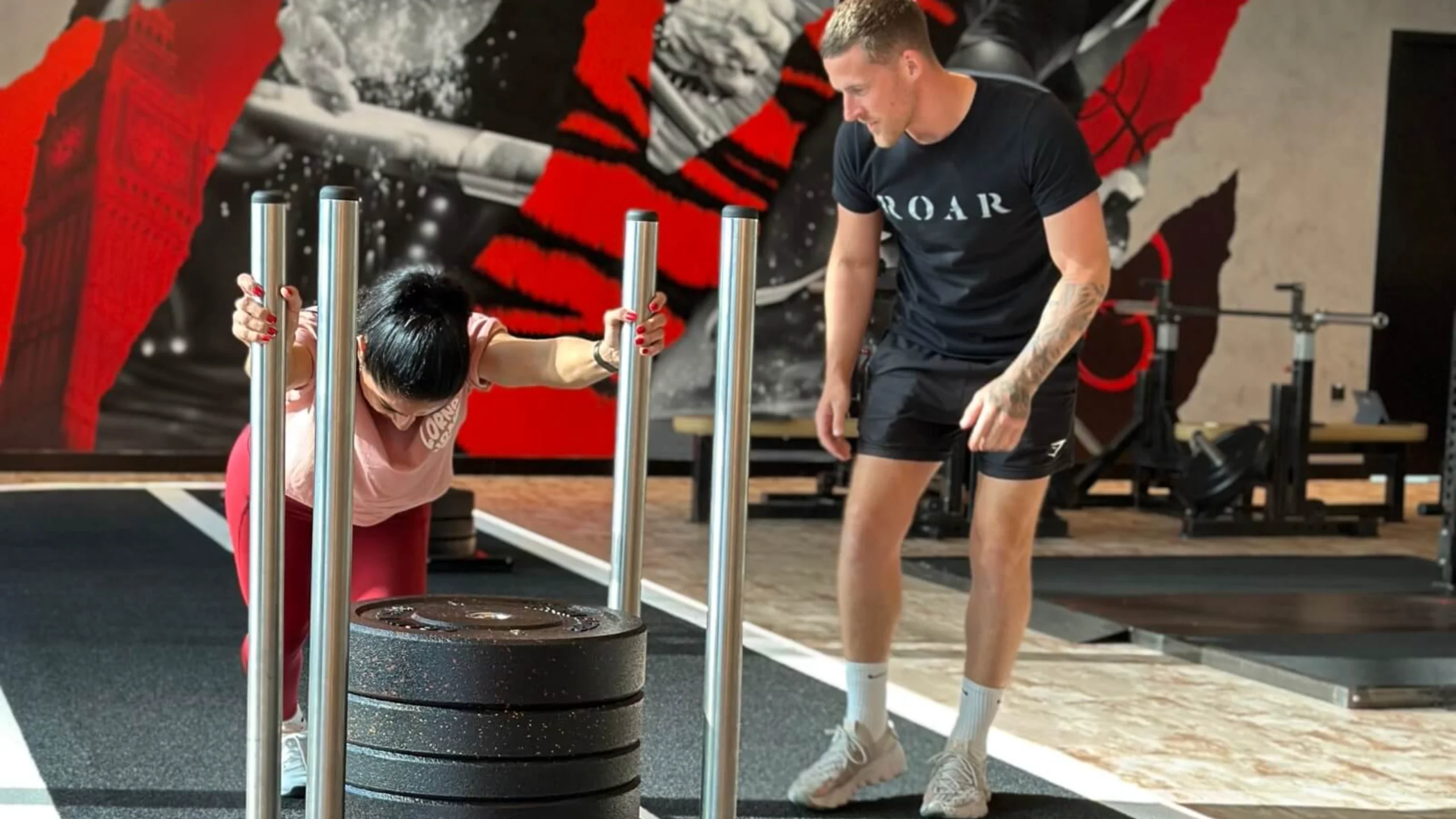Roar Fitness personal trainer coaching a client through a sled push in a fat loss personal training session