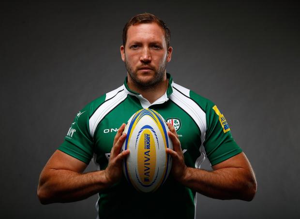 Rugby player George Skivington holding a rugby ball in a studio portrait
