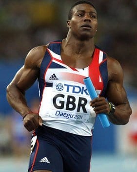 Sprinter Harry Aikines-Aryeetey running in Great Britain kit with a relay baton at the Daegu 2011 World Championships