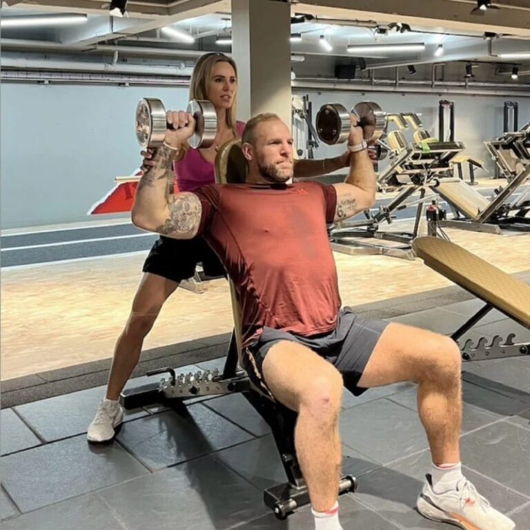 James Haskell doing a seated dumbbell shoulder press with a trainer behind him at ROAR Fitness London