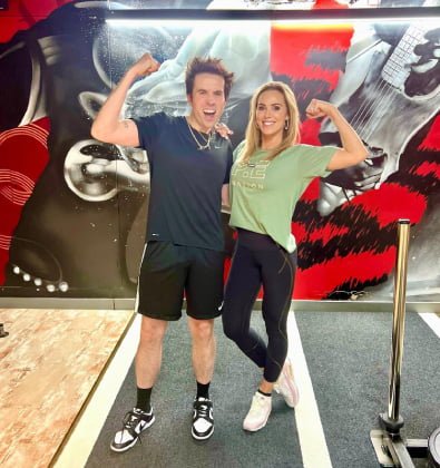 Nick Grimshaw and Sarah Lindsay flexing in front of the gym mural at ROAR Fitness