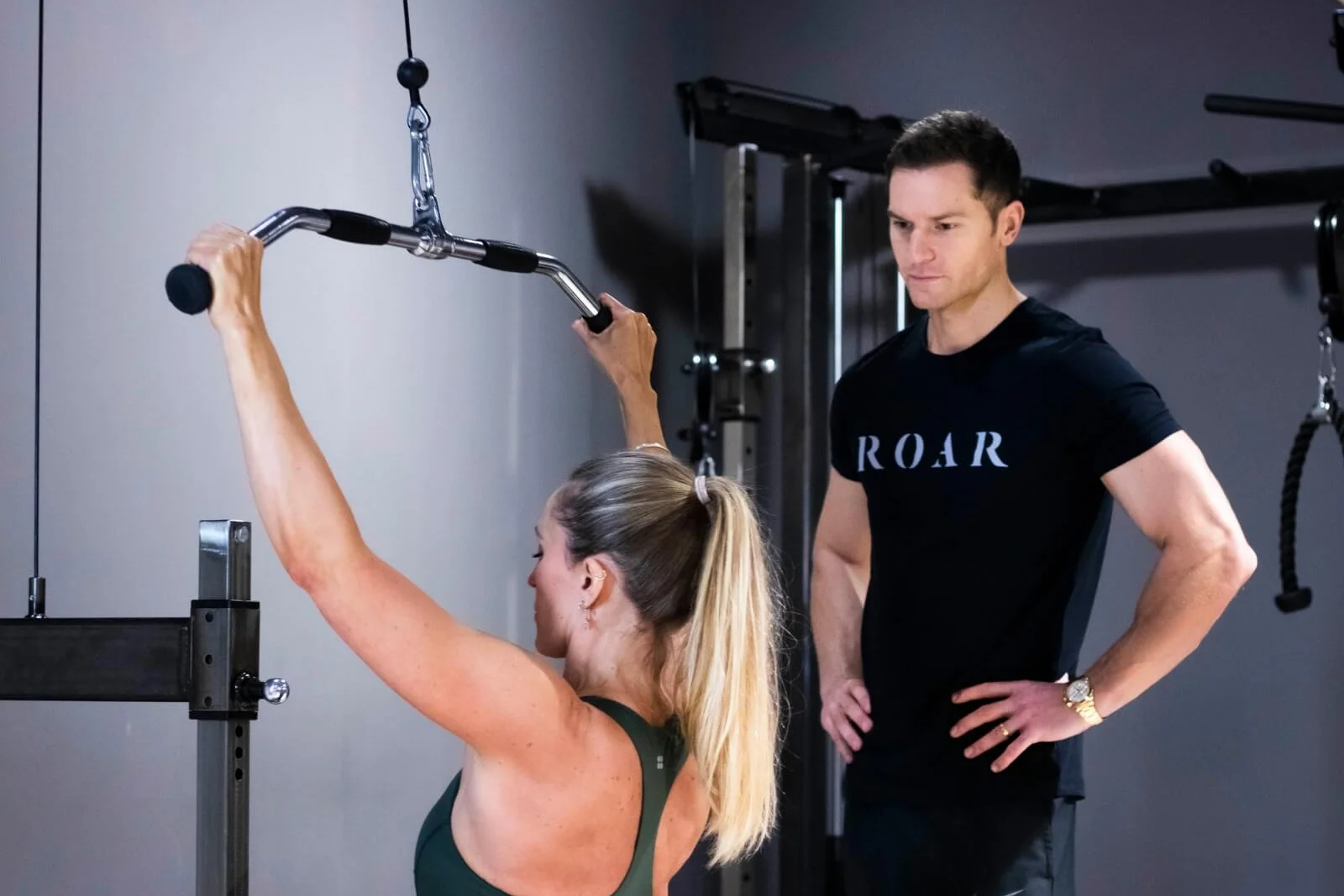 Rich Phillipps watching a client’s form on the cable lat pulldown at Roar Fitness