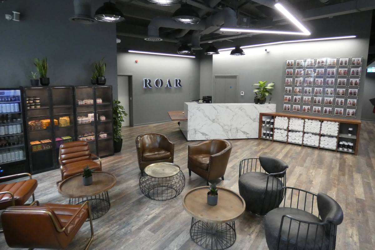Reception and client lounge at ROAR Fitness City of London with a marble front desk, leather armchairs and a client transformation photo wall