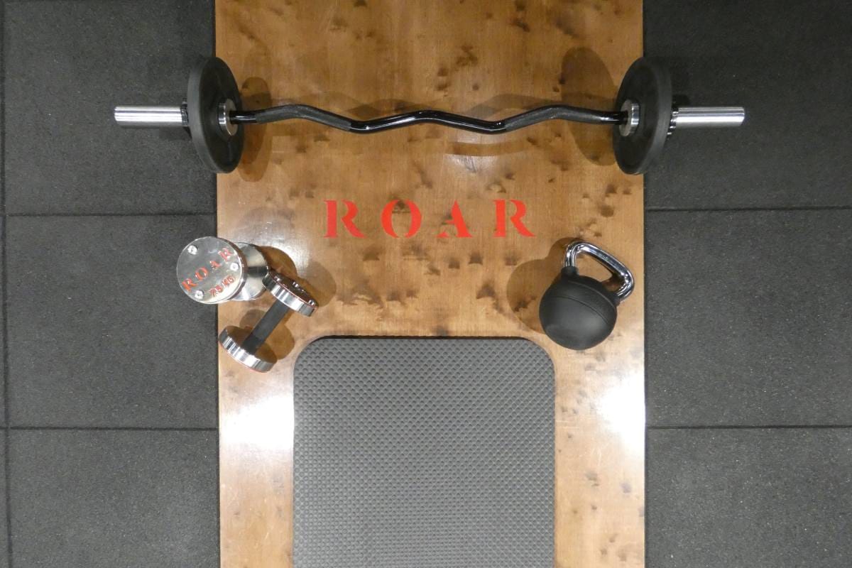 Weight bench, dumbbells and EZ bar on the gym floor at Roar Fitness City of London