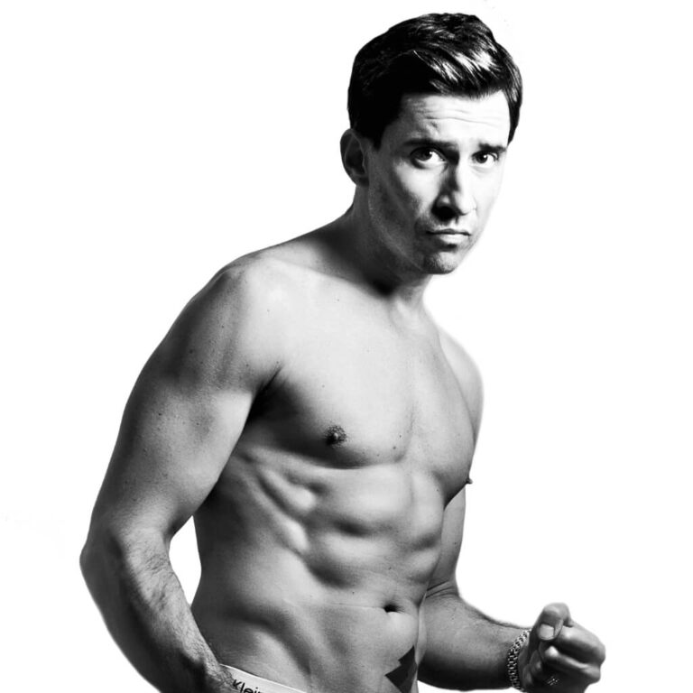 Russell Kane, ROAR Fitness client, posing shirtless in a black and white studio shot