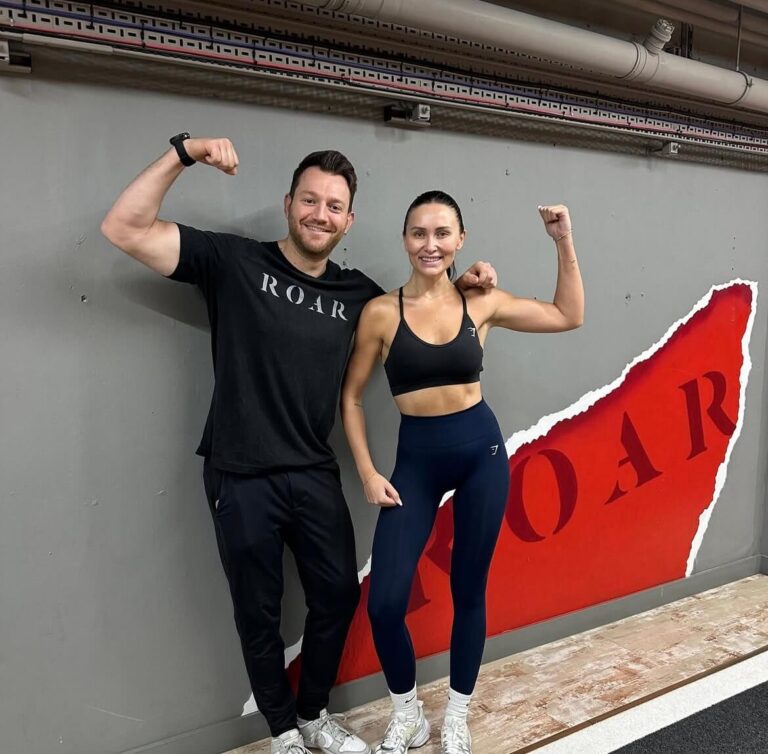 Sarah Ashcroft flexing beside her ROAR personal trainer after a workout at ROAR Fitness London