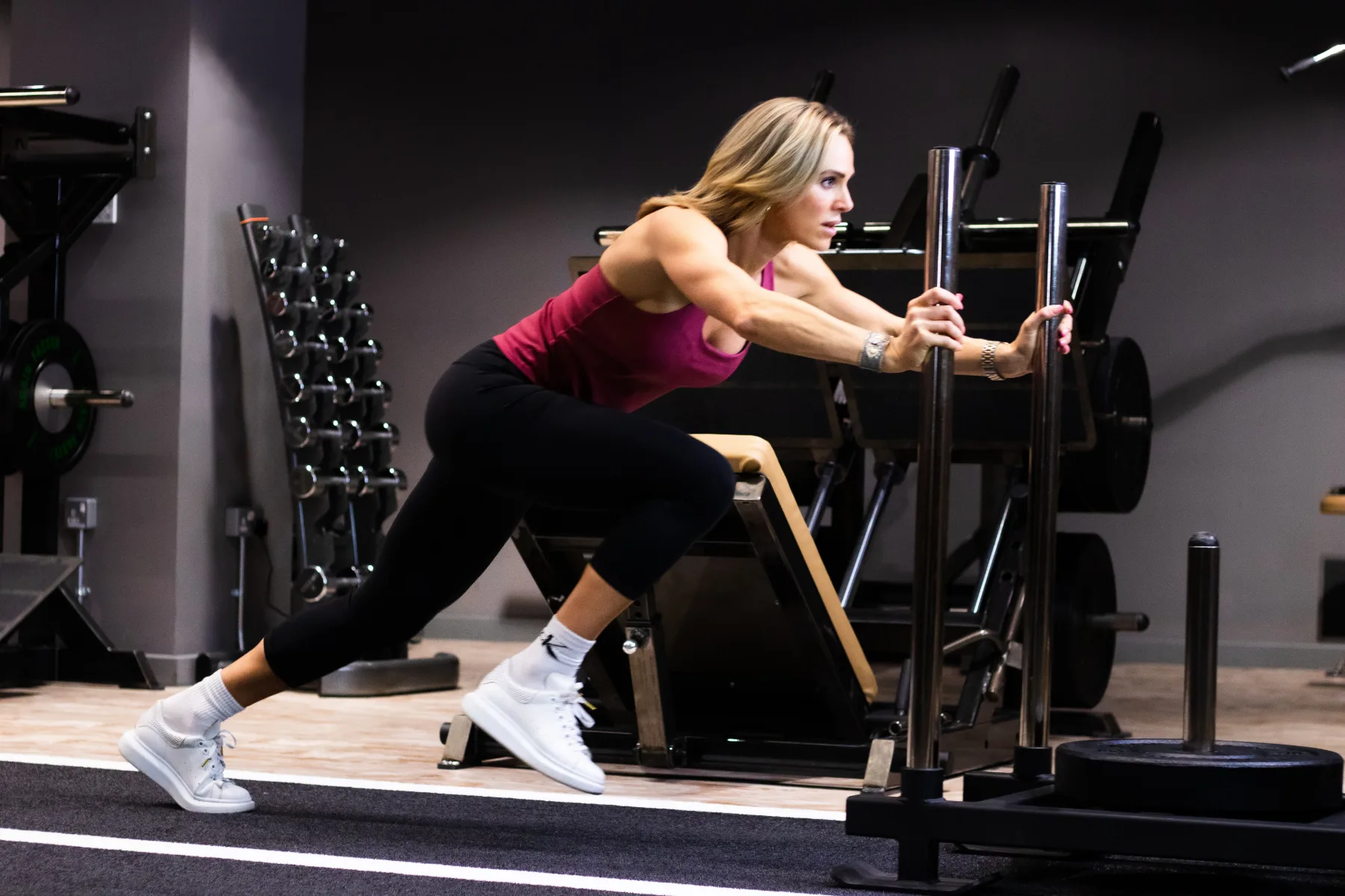 Client driving a weighted sled during a strength training session at Roar Fitness